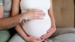 Couple sits together husband touches pregnant wifes belly
