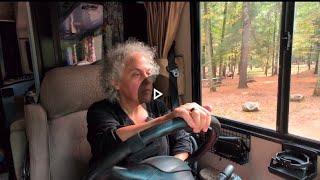 Solo woman driving a 34 Class A RV arriving at a level campsite and setting up water & electric.