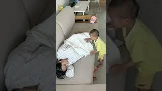 Chinese toddler covers pregnant mother with a blanket as she falls asleep