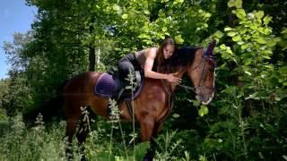 Young woman sits on a horse and hugs it in the forest - Stock video footage