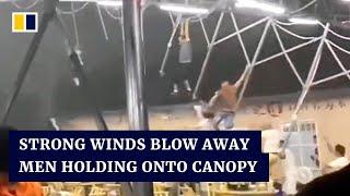 Strong winds in China blow away restaurant staff holding onto canopy