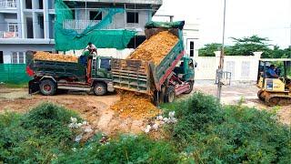 Excellent dozer operator starting new project pushing rock soil into flooded and thick grass