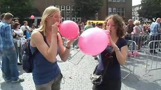 Girls Blowing to Pop Balloons Outdoors