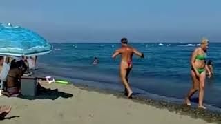 old man running on beach in rainbow g-string