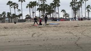 Surfers prepare to enter water and little girl wearing face mask 32220