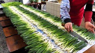 pretty old woman who loves green onions Delicious green onion pancakes baked on a large iron plate