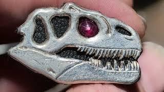 A Star Ruby set in a hand engraved sterling silver allosaurus skull