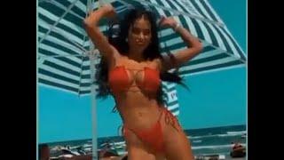 Daniela Crudu dancing in a red bikini at the beach