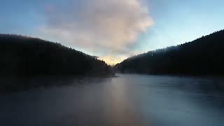 Flying over a lake in misty dawn lights in early morning. 4k Aerial drone view. Belis Romania