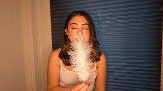 Beautiful girl teasing her nose with a big feather and sneezing