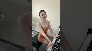 Asian girl in pink dress playing piano elegantly.