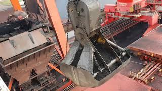 Unloading a 300 meter coal bulk ship. Bucket crane with massive bucket close to the wheelhouse