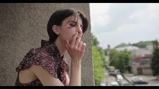 Portret of young brunette woman smoking and thinking in the balcony  Old town sunny weather bad ha