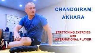 Wrestlers doing stretching exercises with International player at Chandgiram Akhara