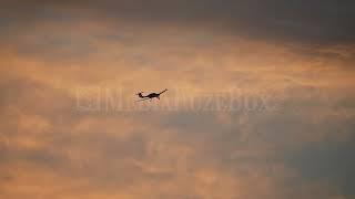 Stock Video - Airplane flying through the sky against colorful sunset