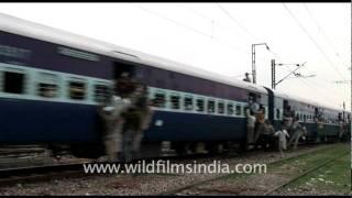 People hanging out of a crowded train in India