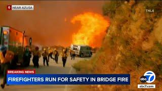 Firefighters run from flames as wildfire advances in Angeles National Forest