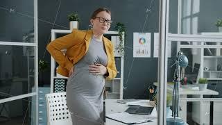 Pregnant businesswoman feeling stomach ache touching belly in workplace