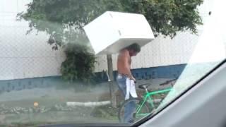 Brazilian man rides a bike with a fridge on his back over cobbles