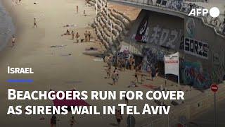 Beachgoers run to take shelter as sirens wail in Tel Aviv  AFP