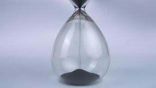 Extreme close up of a transparent hourglass with flowing black...  Indian Stock Footage  Knot9