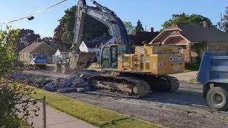 John Deere Excavator Digging Up Road and Loading Dump Truck