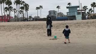 Woman and boy wearing face masks play at beach 32220