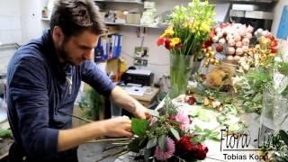 Der Florist zeigt wie er einen Blumenstrauss bindet