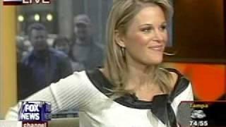 Newswoman bending over in a black leather skirt