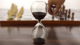 Closeup shot of hands playing chess next to a glass sand clock...  Indian Stock Footage  Knot9