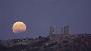 Time lapse Lunar eclipse occurs as full moon rises over ancient Temple in Greece